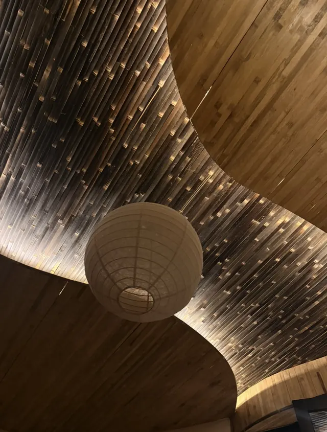 A paper lantern hanging beneath a curved bamboo ceiling