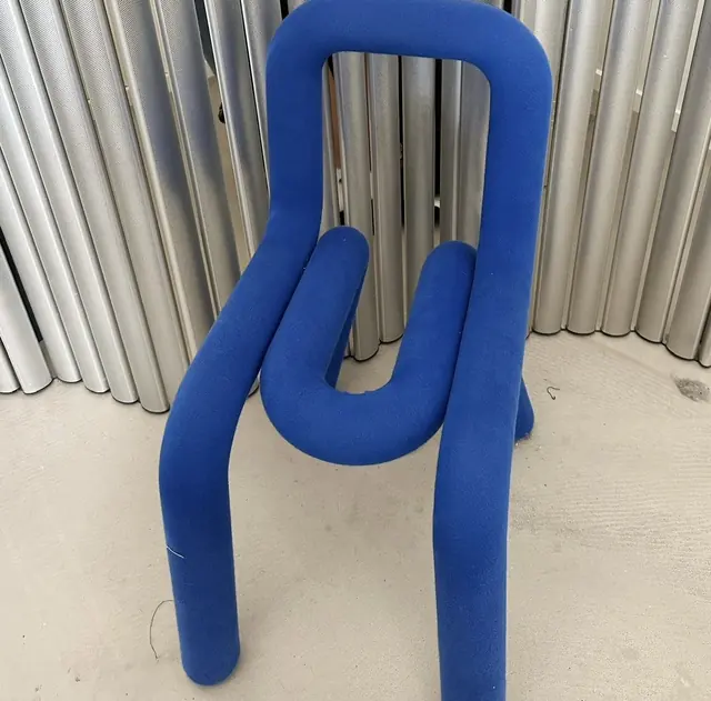 A chair built from a single looped tube upholstered in bright blue